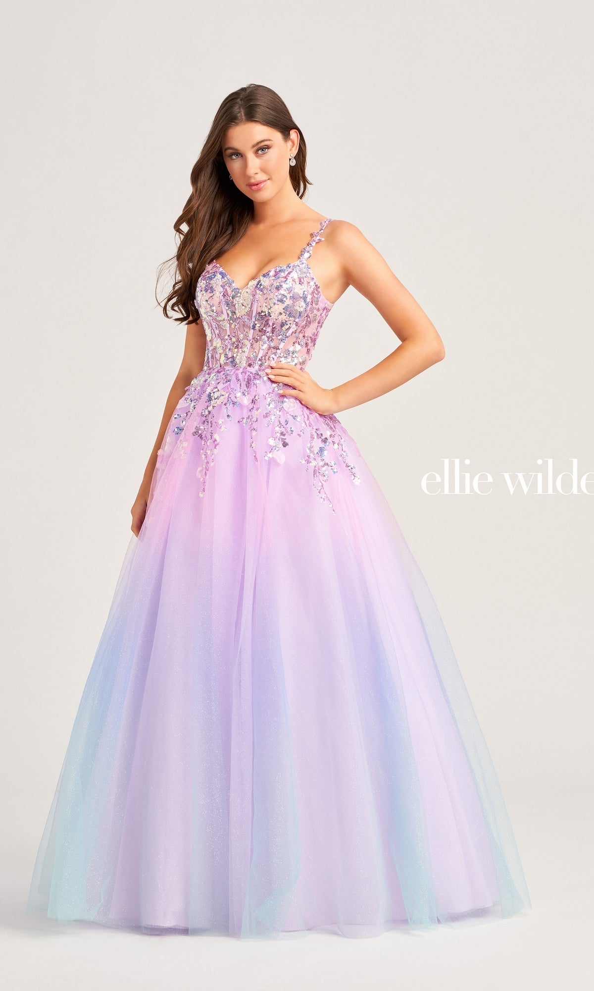 A woman stands gracefully against a plain background wearing the Ellie Wilde Sequin Ombre Prom Ball Gown EW35055, featuring a shimmering ombre effect, sequin embellishments, a full tulle skirt, and thin straps.